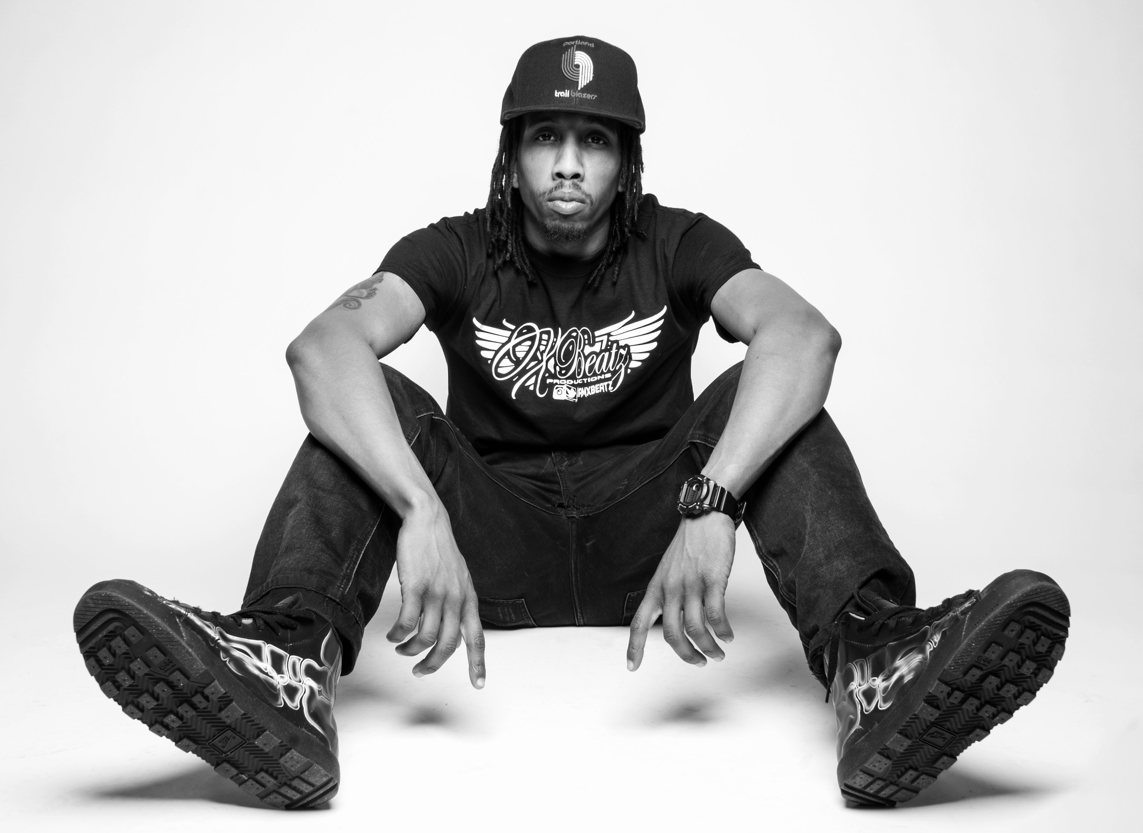 X Beatz in a black hat against a white wall